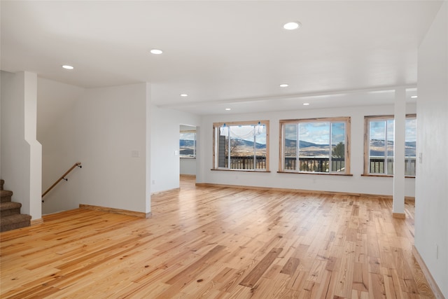 unfurnished living room with recessed lighting, light wood-type flooring, and baseboards