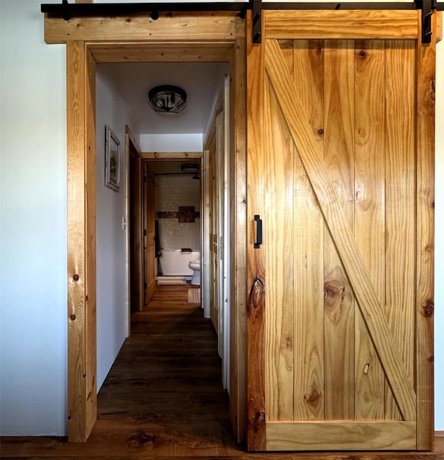 hall featuring a barn door and wood finished floors