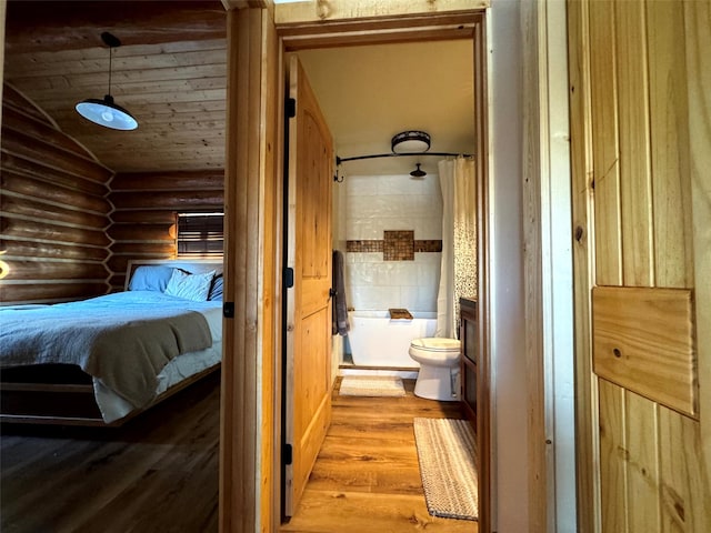 bedroom featuring connected bathroom, vaulted ceiling, wooden ceiling, wood finished floors, and log walls