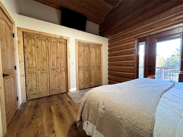 bedroom with wood finished floors, wood ceiling, multiple closets, access to outside, and rustic walls