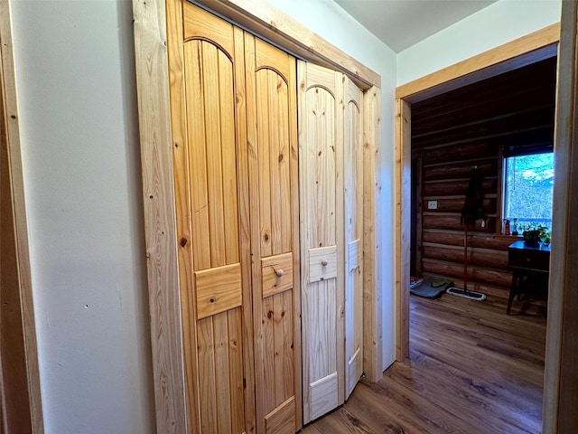 hall with wood finished floors and log walls