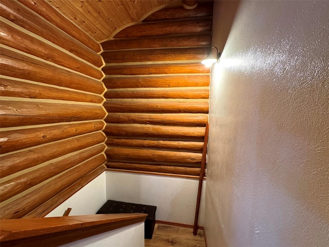 staircase featuring rustic walls, wooden ceiling, wood finished floors, and vaulted ceiling