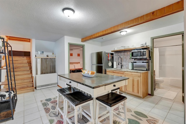 1081 Old Barn Rd, Seeley Lake, MT 59868 - kitchen featuring appliances with stainless steel finishes, light tile patterned flooring, a textured ceiling, light countertops, and light brown cabinetry