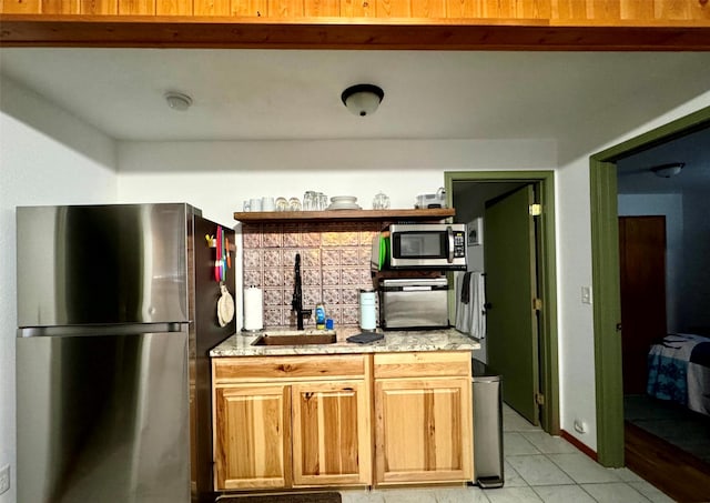 kitchen with a sink, stainless steel appliances, light stone countertops, and light tile patterned flooring