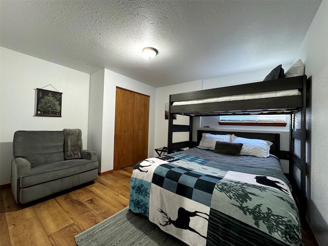 bedroom with a closet, a textured ceiling, and wood finished floors