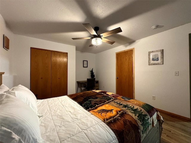 bedroom featuring baseboards, ceiling fan, wood finished floors, a closet, and a textured ceiling