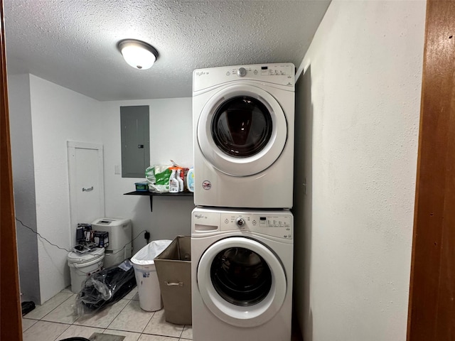 laundry room featuring electric panel, a textured ceiling, light tile patterned floors, stacked washer / drying machine, and laundry area