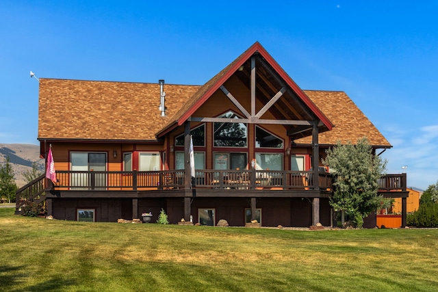 back of house featuring a lawn, a wooden deck, and a shingled roof