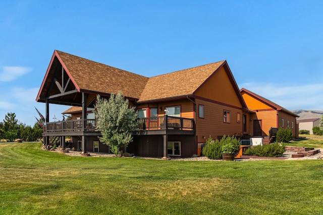 rear view of house featuring a deck, a yard, and a shingled roof