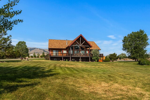 rear view of house with a yard and a deck with mountain view