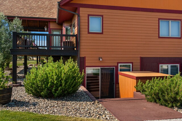 back of property with a deck and a shingled roof