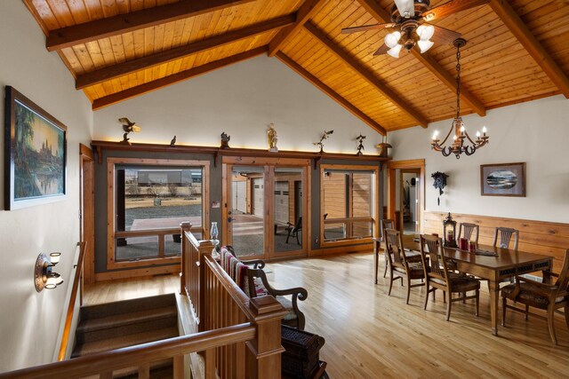 dining area featuring beamed ceiling, high vaulted ceiling, wood finished floors, an inviting chandelier, and wooden ceiling