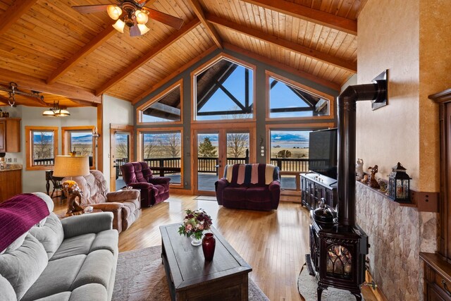 living area with beamed ceiling, hardwood / wood-style floors, and a wood stove