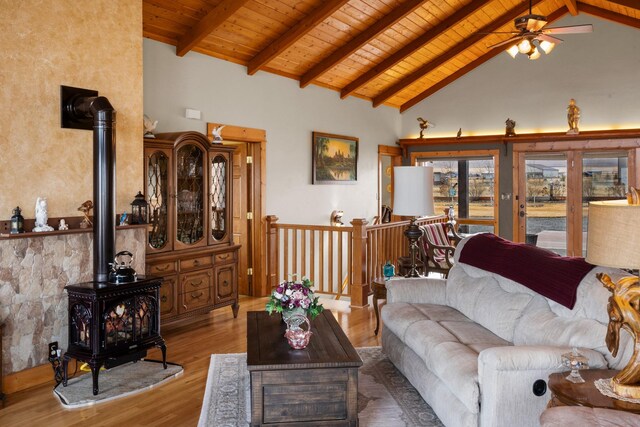 living area featuring beamed ceiling, wood ceiling, a wood stove, and wood finished floors