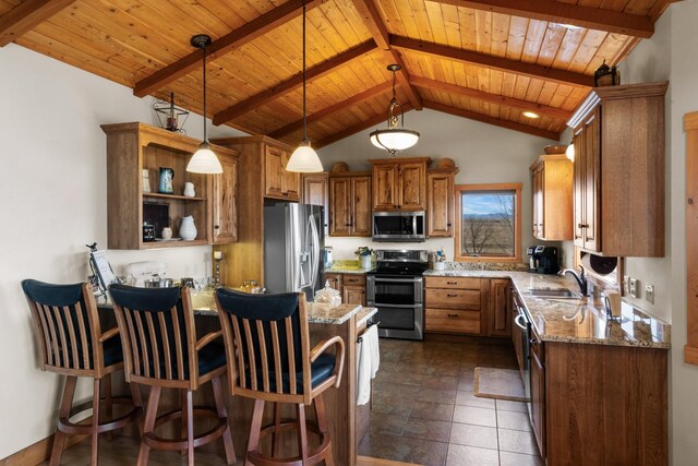 kitchen with light stone counters, brown cabinetry, a peninsula, a sink, and appliances with stainless steel finishes
