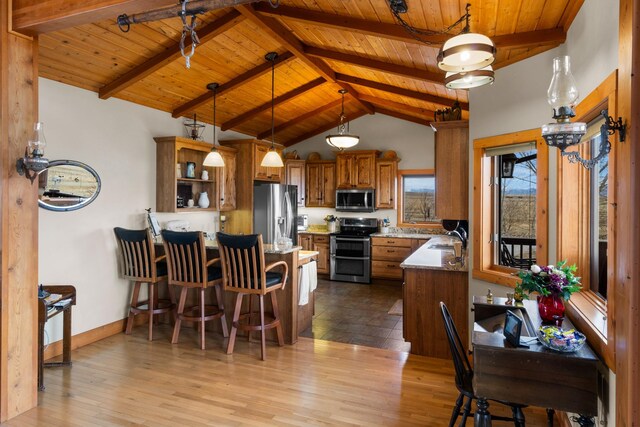 kitchen featuring a sink, brown cabinets, a peninsula, stainless steel appliances, and open shelves