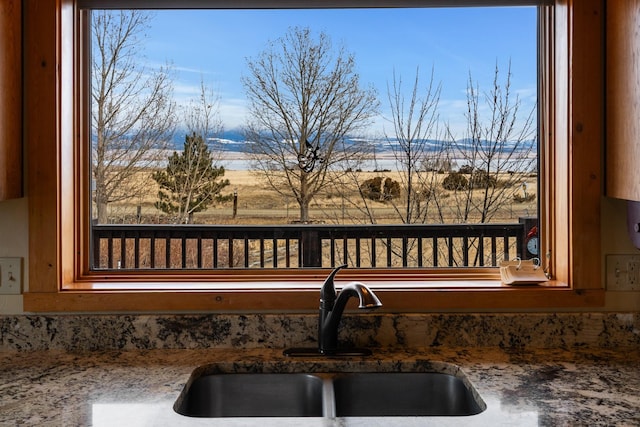 interior details featuring brown cabinetry, stone countertops, and a sink