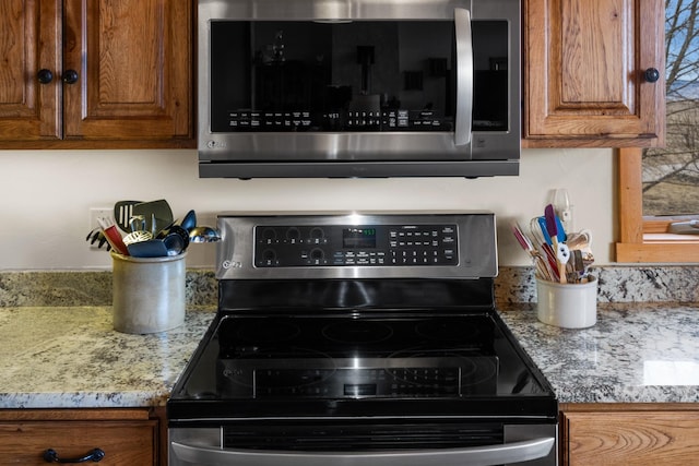 interior details with brown cabinetry, stainless steel appliances, and light stone countertops