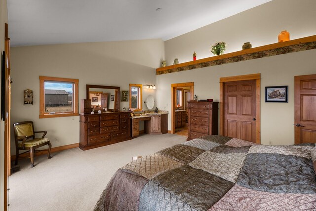 bedroom featuring baseboards, lofted ceiling, light colored carpet, and connected bathroom