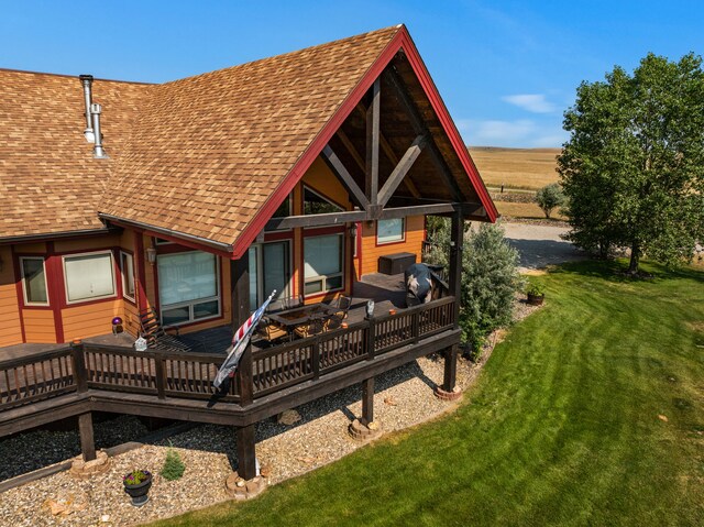 back of property featuring a yard, a deck, and a shingled roof