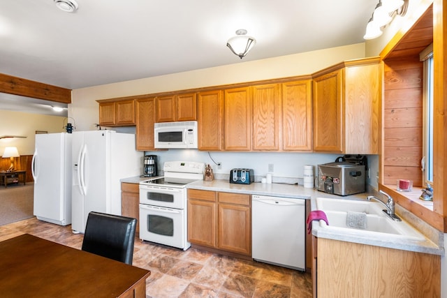 kitchen with brown cabinetry, white appliances, light countertops, and a sink