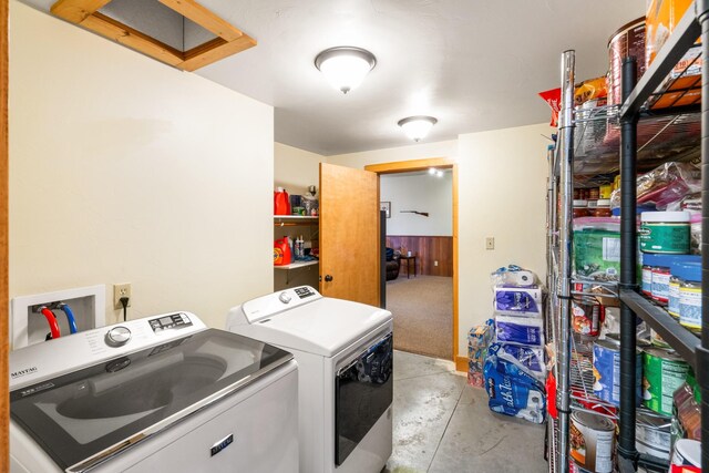 clothes washing area with attic access, washing machine and dryer, laundry area, and wood walls