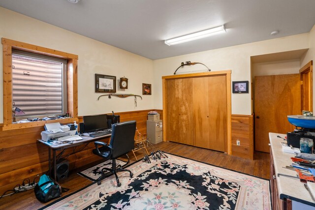 home office with wood finished floors, wood walls, and wainscoting