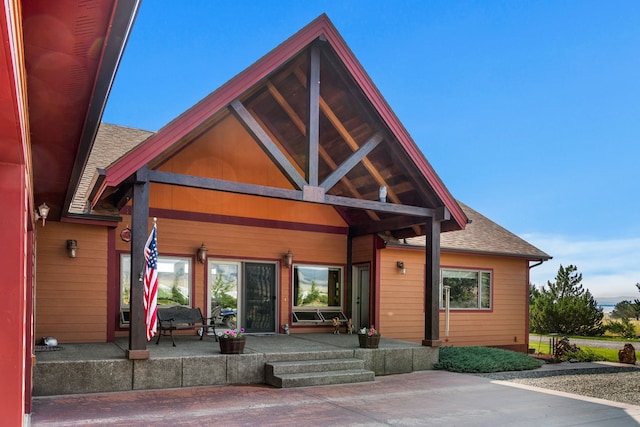exterior space with a porch and a shingled roof