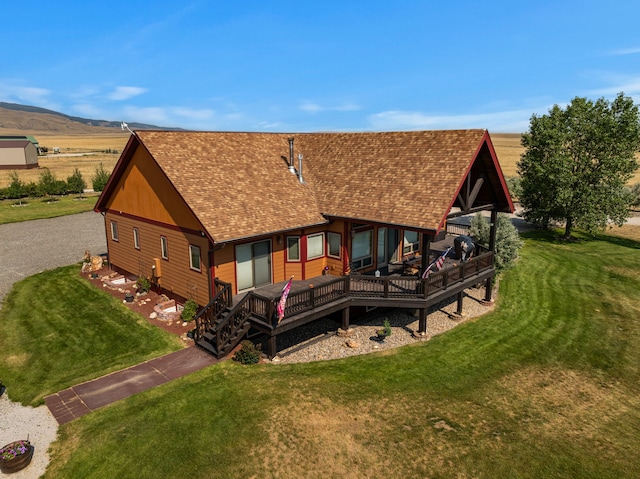 back of property with a deck, aphalt driveway, a yard, and a shingled roof