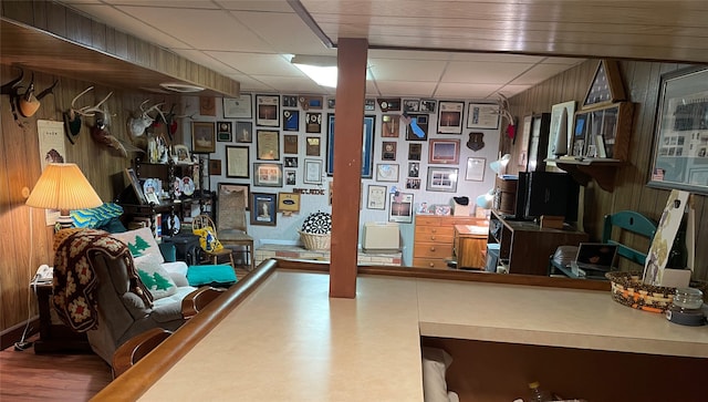 finished basement with wooden walls, wood finished floors, and a drop ceiling