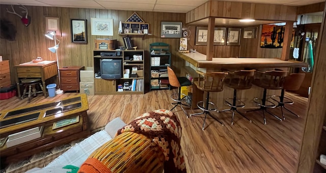 bar with a dry bar, wood finished floors, wood walls, and a drop ceiling