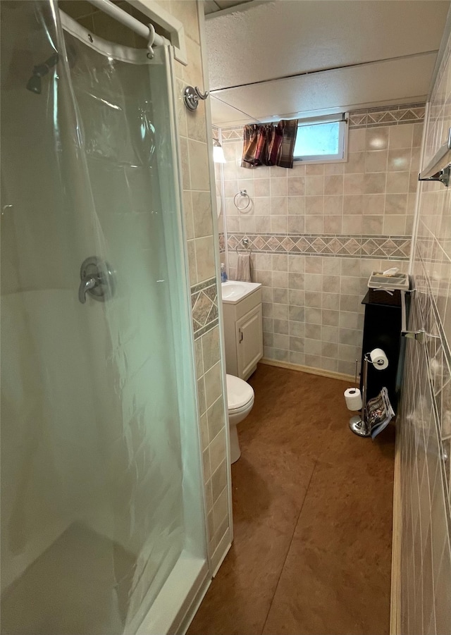 full bathroom with a shower stall, vanity, tile walls, and toilet