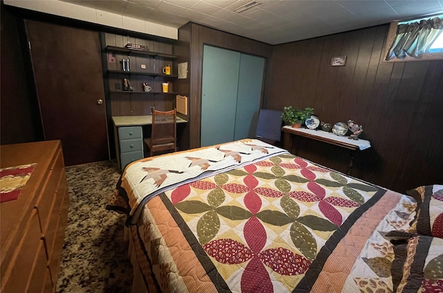 carpeted bedroom featuring a closet and wood walls