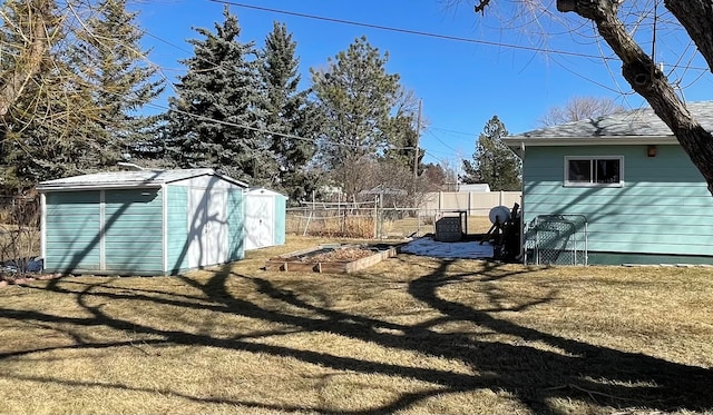 view of yard featuring an outdoor structure, a garden, fence, and a shed