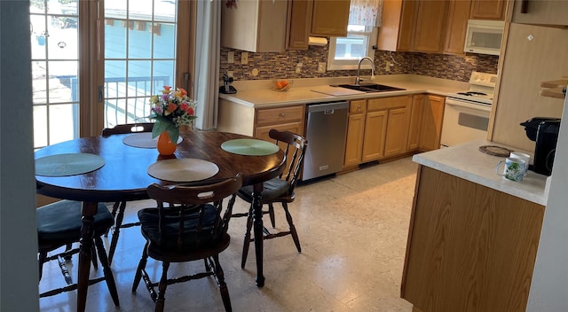 kitchen featuring white appliances, light floors, a sink, decorative backsplash, and light countertops