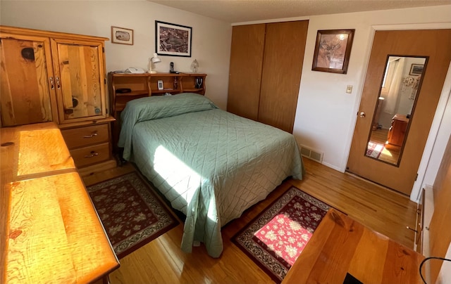 bedroom with a closet, visible vents, and wood finished floors