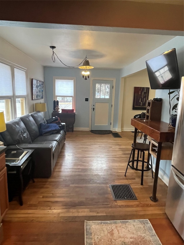 living area featuring visible vents, baseboards, and wood finished floors