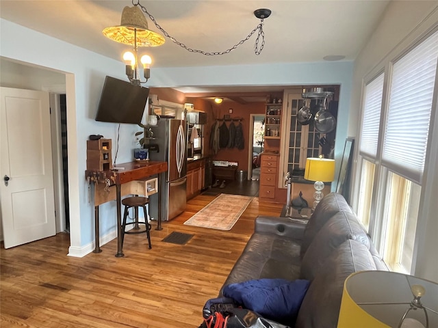 living area featuring an inviting chandelier, baseboards, and light wood-style floors