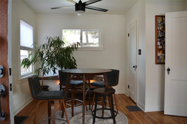 dining space with visible vents, a ceiling fan, baseboards, and wood finished floors