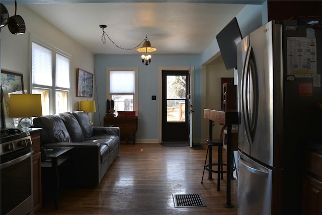 living room with dark wood-style floors, visible vents, and baseboards