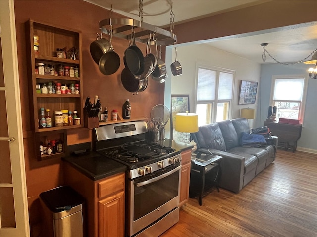 kitchen featuring dark countertops, open floor plan, gas stove, light wood-style floors, and brown cabinetry