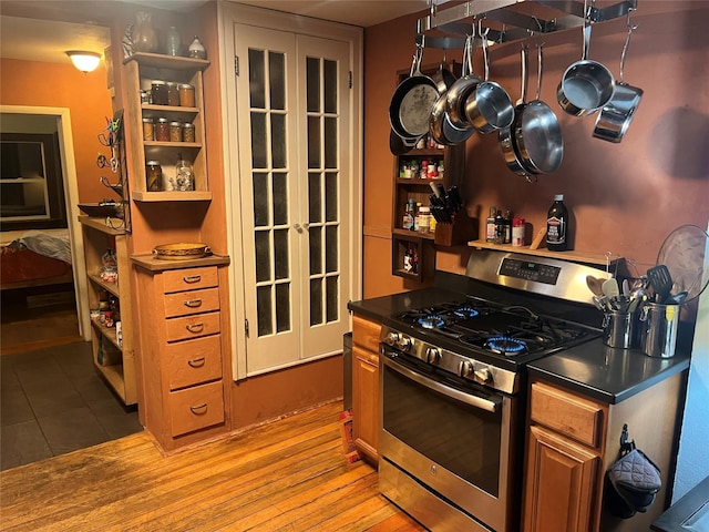 kitchen featuring dark countertops, light wood finished floors, open shelves, gas range, and brown cabinets