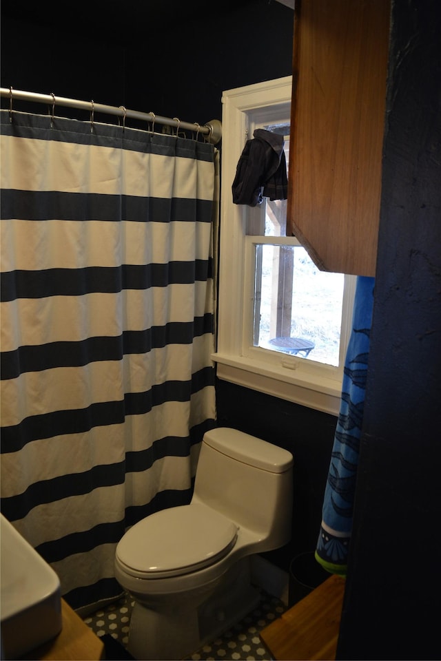 full bathroom with toilet and a shower with shower curtain