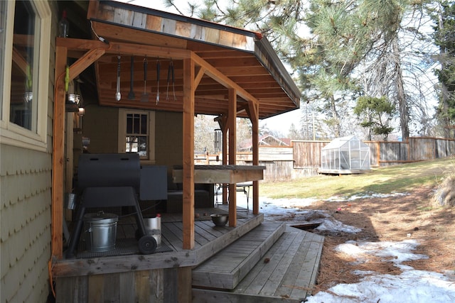 deck featuring a greenhouse, an outdoor structure, and a fenced backyard