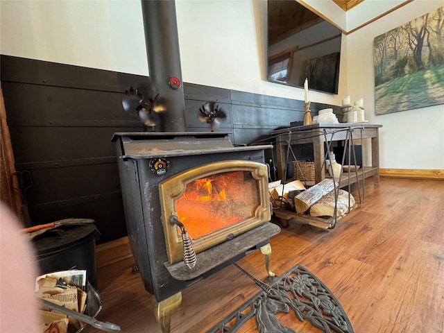 interior details with a wood stove, wood finished floors, and baseboards