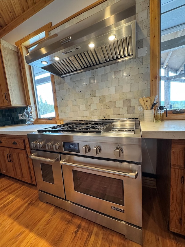 kitchen featuring range hood, range with two ovens, light countertops, and light wood finished floors