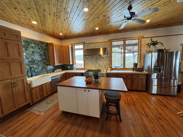 kitchen featuring dark wood finished floors, a sink, butcher block countertops, stainless steel appliances, and wall chimney exhaust hood