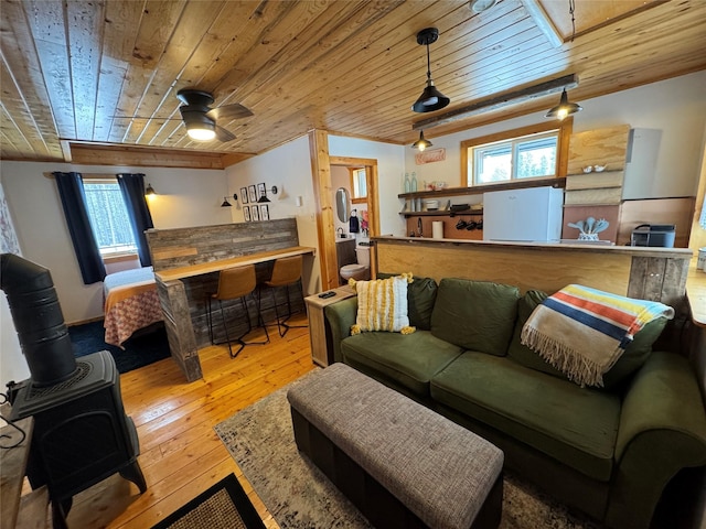 living room with wood ceiling, a wood stove, a ceiling fan, and hardwood / wood-style floors