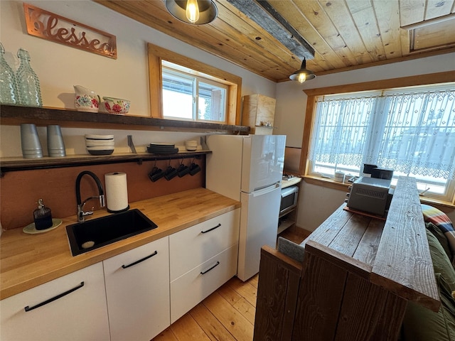 kitchen featuring open shelves, freestanding refrigerator, a sink, wood ceiling, and white cabinetry