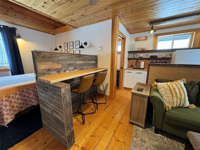 interior space featuring light wood finished floors, wooden ceiling, a bar, and vaulted ceiling